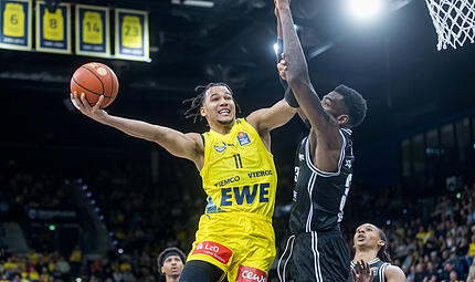 EWE Baskets Oldenburg vs. BMA365 Bamberg Baskets Nicholas Tischler (mit Ball) verschafft sich beim Korbabschluss Platz gegen den besten Shotblocker der Liga, EJ Onu.
