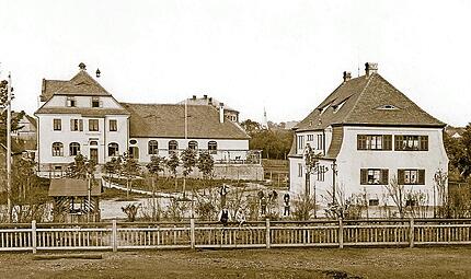 Ein Bilderbuch-Ensemble von 1908: das Eisenbahnerhaus mit der Gaststätte „Fränkischer Hof“ dahinter. Ein Park mit jungen Kastanien verbindet die beiden in Reformarchitektur des frühen 20. Jahrhunderts errichteten Gebäude. Ein Bilderbuch-Ensemble von 1908: das Eisenbahnerhaus mit der Gaststätte „Fränkischer Hof“ dahinter. Ein Park mit jungen Kastanien verbindet die beiden in Reformarchitektur des frühen 20. Jahrhunderts errichteten Gebäude.