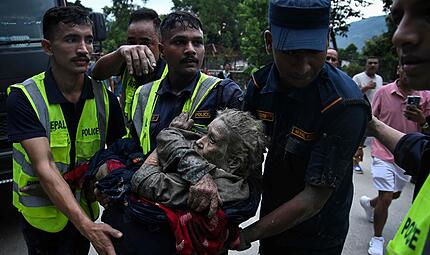 Flutkatastrophe in Nepal 2026 Rescuers carry in their arms a flood survivor, following flash floods and a landslide disaster in Devghat, in the Nepal's Nuwakot district on August 26, 2026. A massive flood and landslide disaster on the Nepal-Tibet border killed at least 103 people on August 26, 2026 and left several hundred missing, many of them foreign tourists. Aid workers said entire settlements had been "wiped out". Some 403 tourists -- 341 of them foreigners -- were unaccounted for several hours after the disaster struck, according to the tourism ministry. (Photo by PRAKASH MATHEMA / AFP)